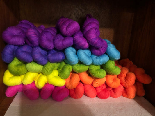 A rainbow of neon dyed yarns sits in a neatly organized pile.